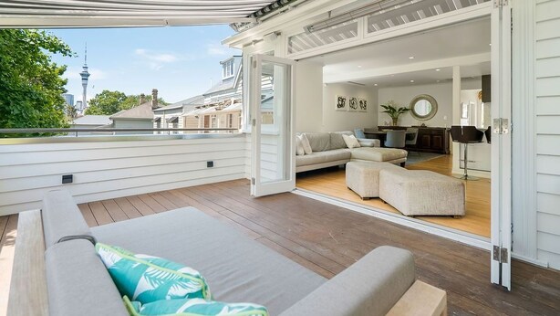 Une terrasse ouverte offrant une vue sur les gratte-ciel de la ville, un canapé et un coin repas.