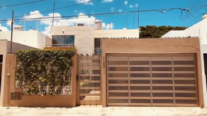 A gated entrance with a metal gate and a decorative wall with climbing plants. - Habitación Independiente al Norte de Mérida (Mérida)