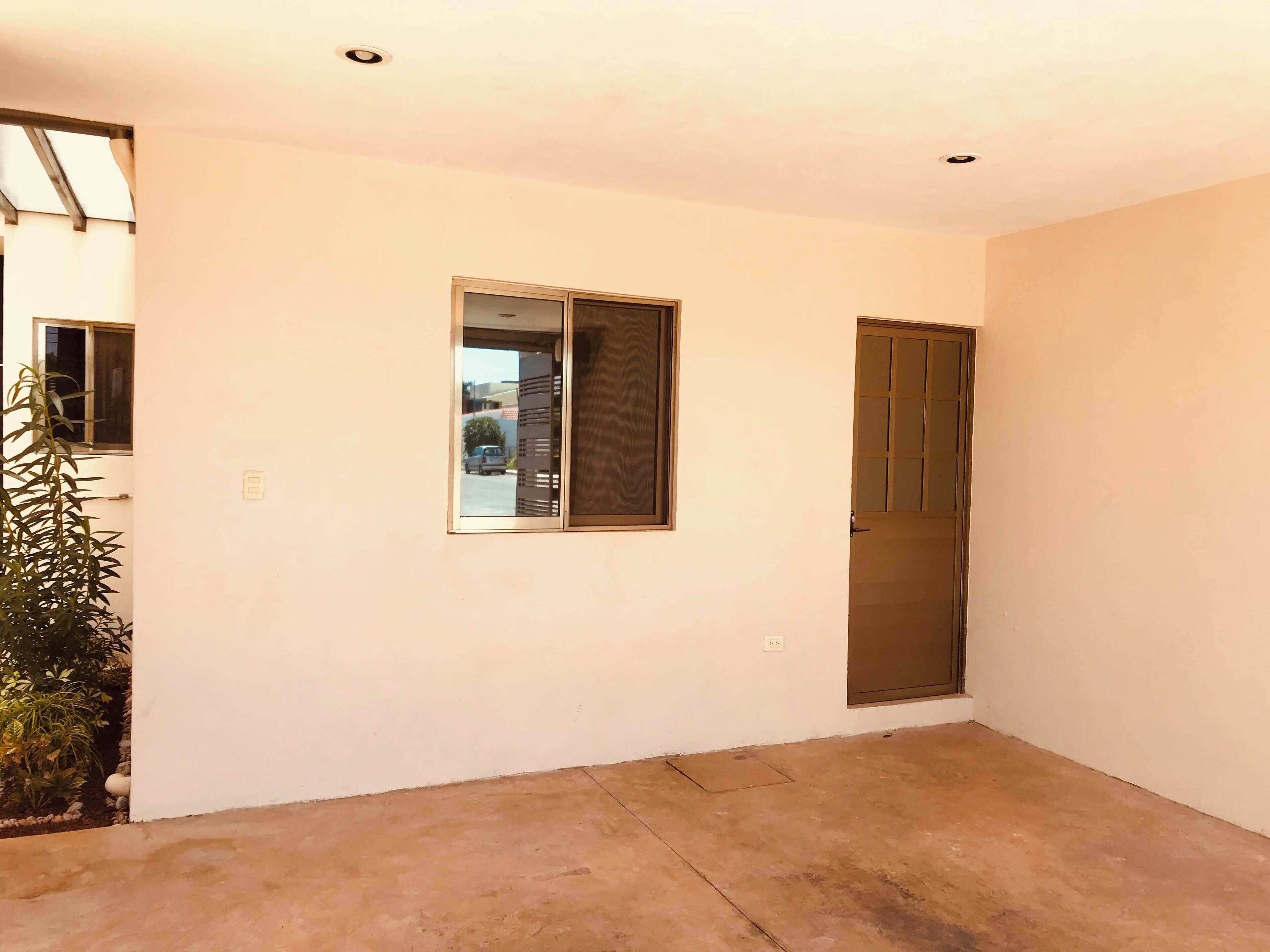 A room with a single window, a door, and a concrete floor.