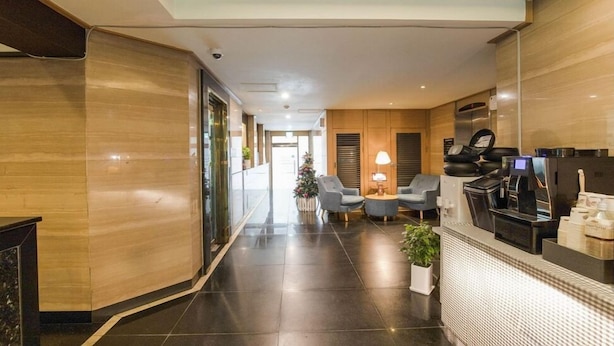 A hotel lobby with a modern design, featuring a reception desk, seating area, and a coffee machine. - Nowon Luxe hotel (Seoul)
