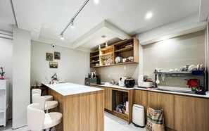 A modern kitchen with a central island, wooden cabinets, and a built-in oven. - Nowon Luxe hotel (Seoul)