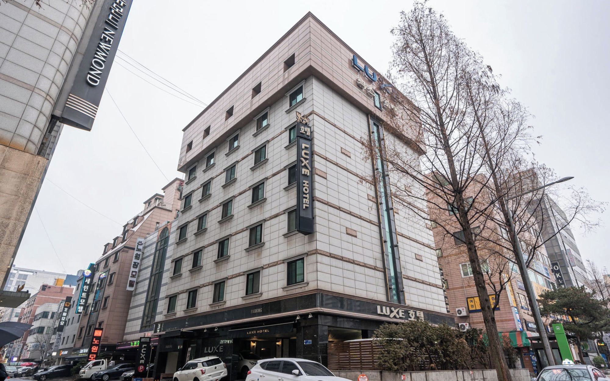 A multi-story hotel with a prominent 'LUXE HOTEL' sign, a parking garage entrance, and a modern architectural design.