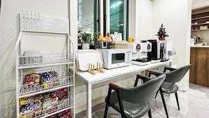 A modern kitchen with a white countertop, a microwave, a coffee machine, and a small Christmas tree. - Nowon Luxe hotel (Seoul)