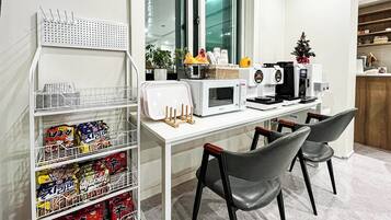 Eine moderne Küche mit Mikrowelle, Toaster und Kaffeemaschine auf der Arbeitsplatte. Zwei Stühle und eine kleine Weihnachtstanne stehen rechts.