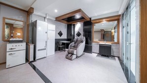 A modern bathroom with a shower, a massage chair, and a vanity with a mirror. - Nowon Luxe hotel (Seoul)