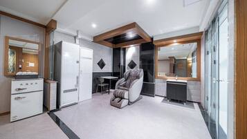 A modern bathroom with a shower, a massage chair, and a vanity with a mirror.