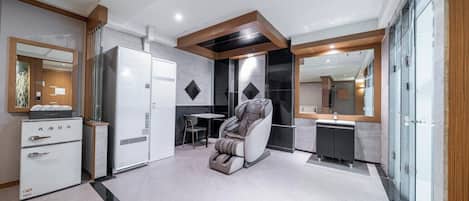 Un baño moderno con ducha, sillón de masaje y tocador con espejo.