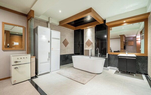 A modern bathroom with a freestanding bathtub, a built-in vanity, and a separate refrigerator. - Nowon Luxe hotel (Seoul)