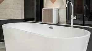 A modern bathroom with a freestanding bathtub, a wall-mounted air conditioner, and a chrome faucet. - Nowon Luxe hotel (Seoul)