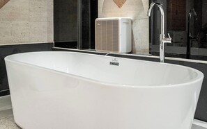 A modern bathroom with a freestanding bathtub, a wall-mounted air conditioner, and a chrome faucet. - Nowon Luxe hotel (Seoul)