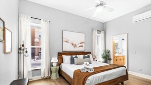 A bedroom with a large bed, a ceiling fan, a window with curtains, a bedside table, and a mirror. - New Luxury Condo - Canal Park, Lakeview, Game Tables, Sleeps 8 (Duluth)
