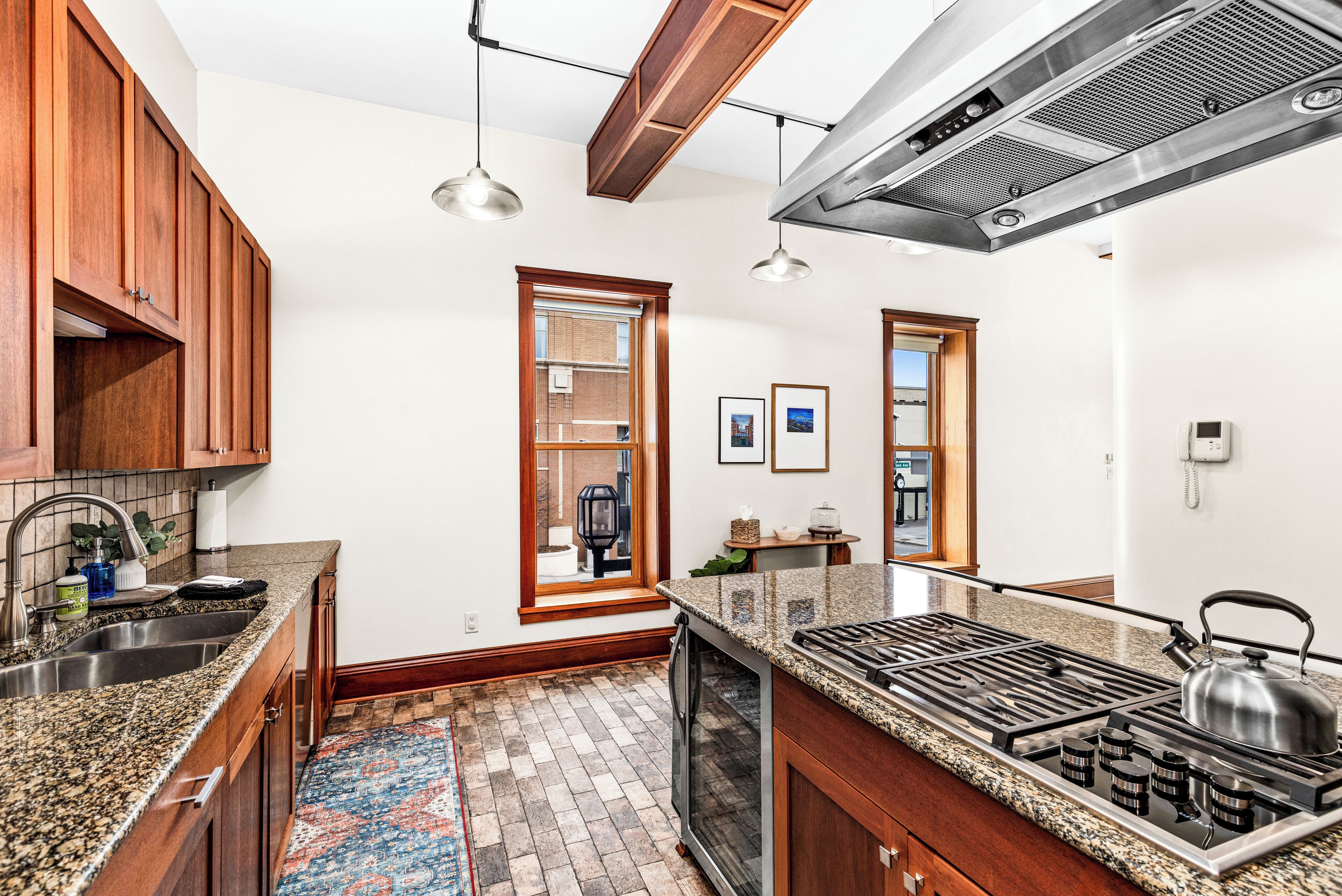 A kitchen with granite countertops, wooden cabinets, a gas stove, and a large window.