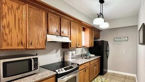 A kitchen with wooden cabinets, a microwave, a stove, and a refrigerator. - FLIP FLOP INN, 5MIN TO CRUISE AND BEACH (Galveston)
