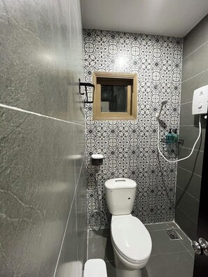 A bathroom with a toilet, a shower, and a small window. - Lanni House (Da Nang)