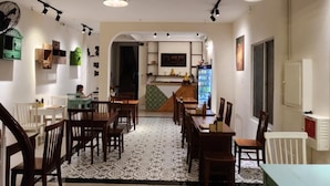 A spacious dining area with multiple tables and chairs, a central island with a counter, and pendant lighting. - Lanni House (Da Nang)