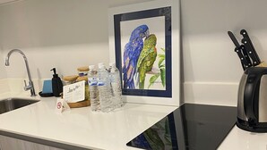 Ett modernt kök med en inbyggd mikrovågsugn, en digital våg och ett inramat konstverk som föreställer papegojor.