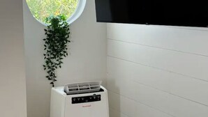 Et værelse med et vindue, et vægmonteret TV og en hvid aircondition.