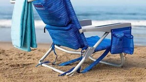 En strandstol med et håndklæde på en sandstrand.