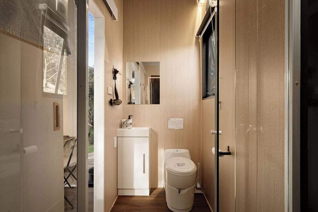 A compact bathroom with a toilet, sink, and mirror.