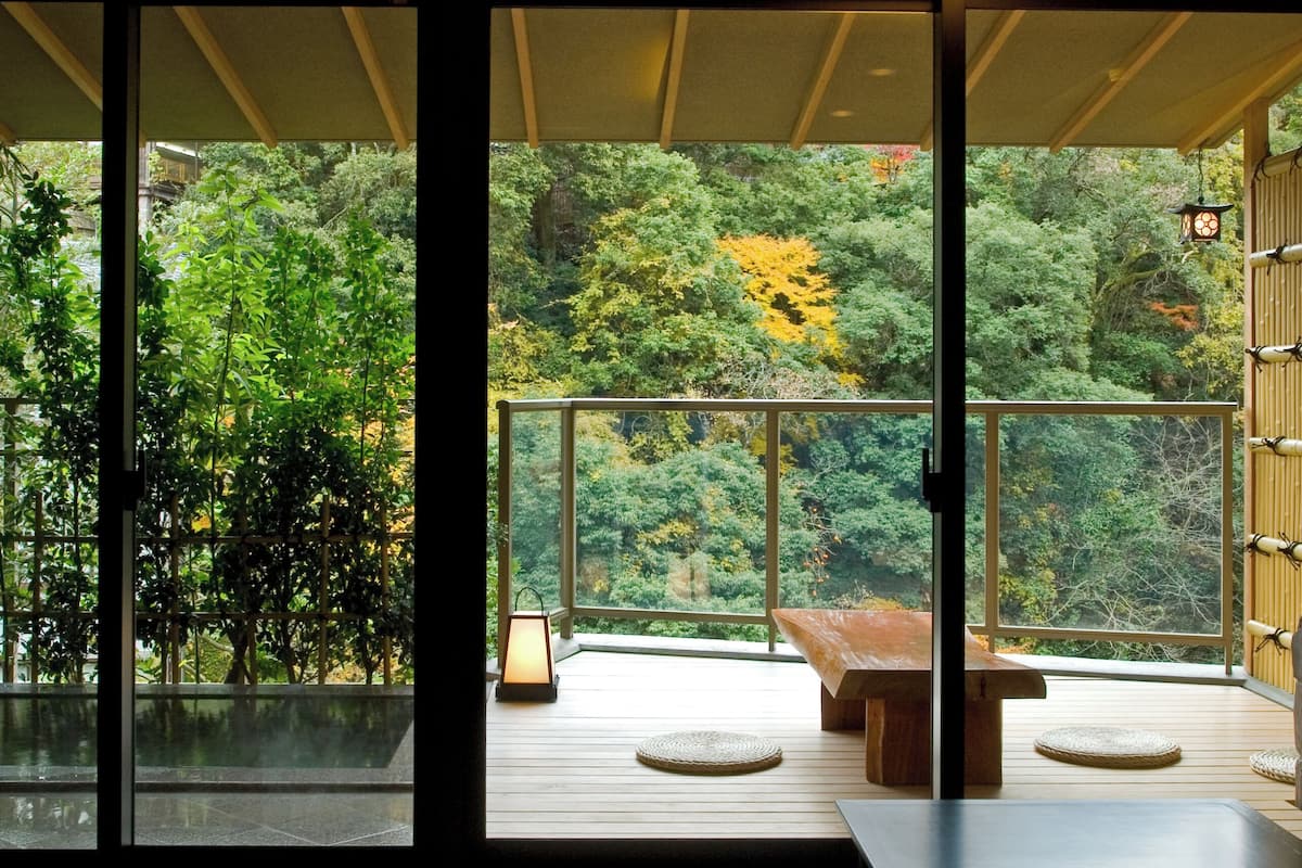 A modern interior with a large sliding glass door leading to an outdoor balcony with a view of a forested area.