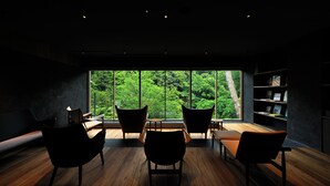 Una habitación moderna con un ventanal grande, suelo de madera y sillas negras.