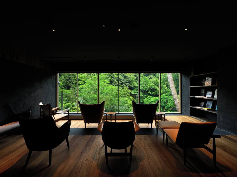 Quarto moderno com uma janela ampla, piso de madeira e cadeiras pretas.