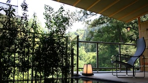 Un área de piscina interior tranquila con una silla y un farol, rodeada de abundante follaje.