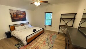 A bedroom with a bed, a ceiling fan, a window, a painting, and a desk. - Spacious Cottage in Rogers. Central: bike trails, restaurants, work, everything! (Rogers)