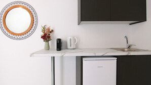 A modern kitchen with a white countertop, a built-in dishwasher, a coffee maker, and a decorative mirror with a geometric frame.