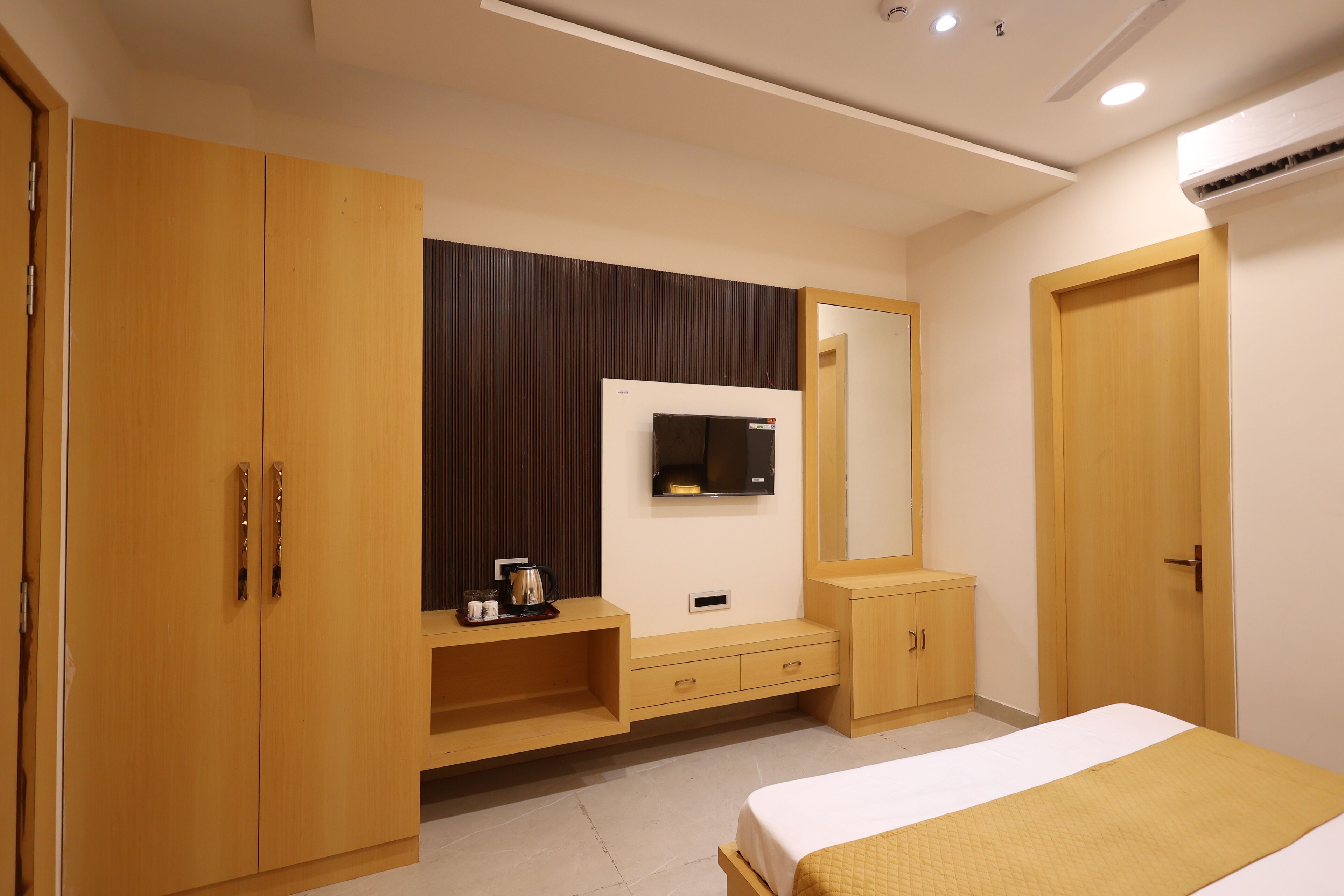 Un dormitorio moderno con cama, armario, tocador y televisor instalado en la pared.