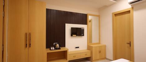 Un dormitorio moderno con cama, armario, tocador y televisor instalado en la pared.