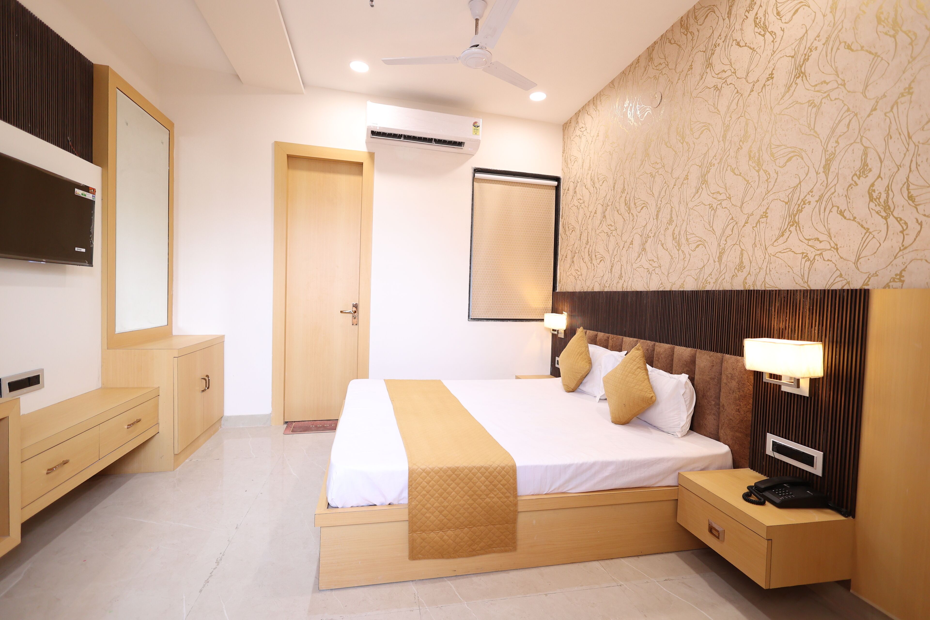 Una habitación de hotel con cama, mesita de noche y un espejo grande.