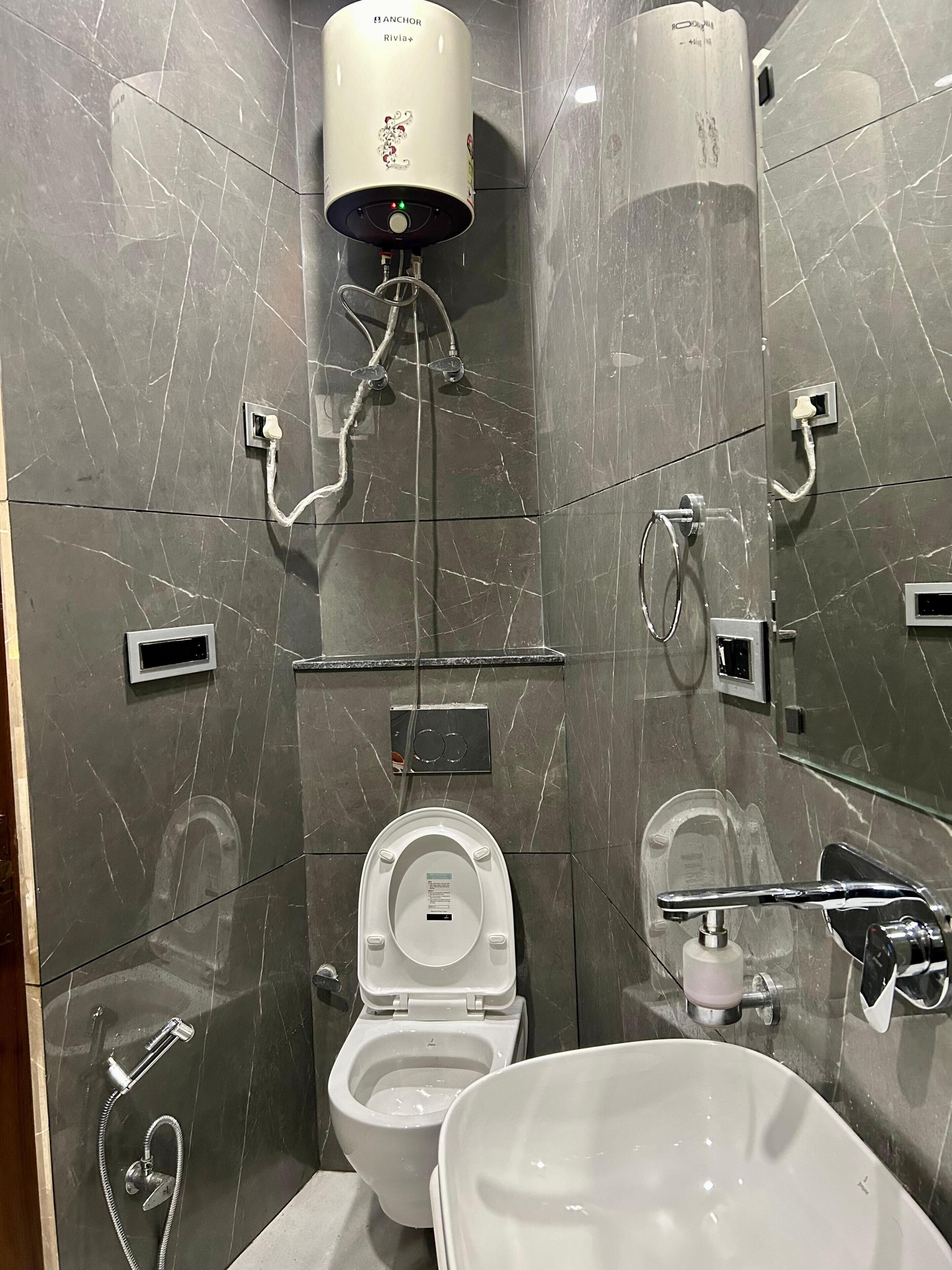 A modern bathroom with a toilet, bidet, and a large mirror.