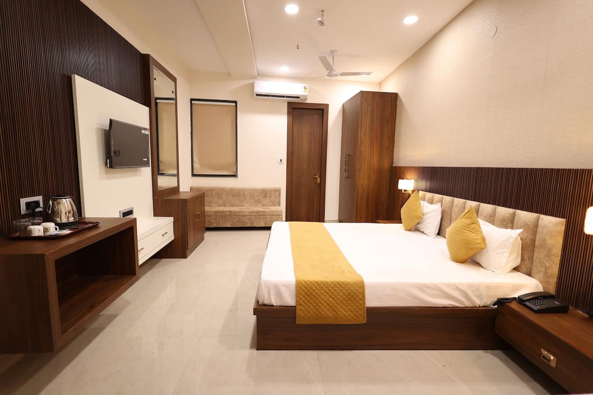 A hotel room with a bed, bedside tables, a TV, a wardrobe, and a mirror.