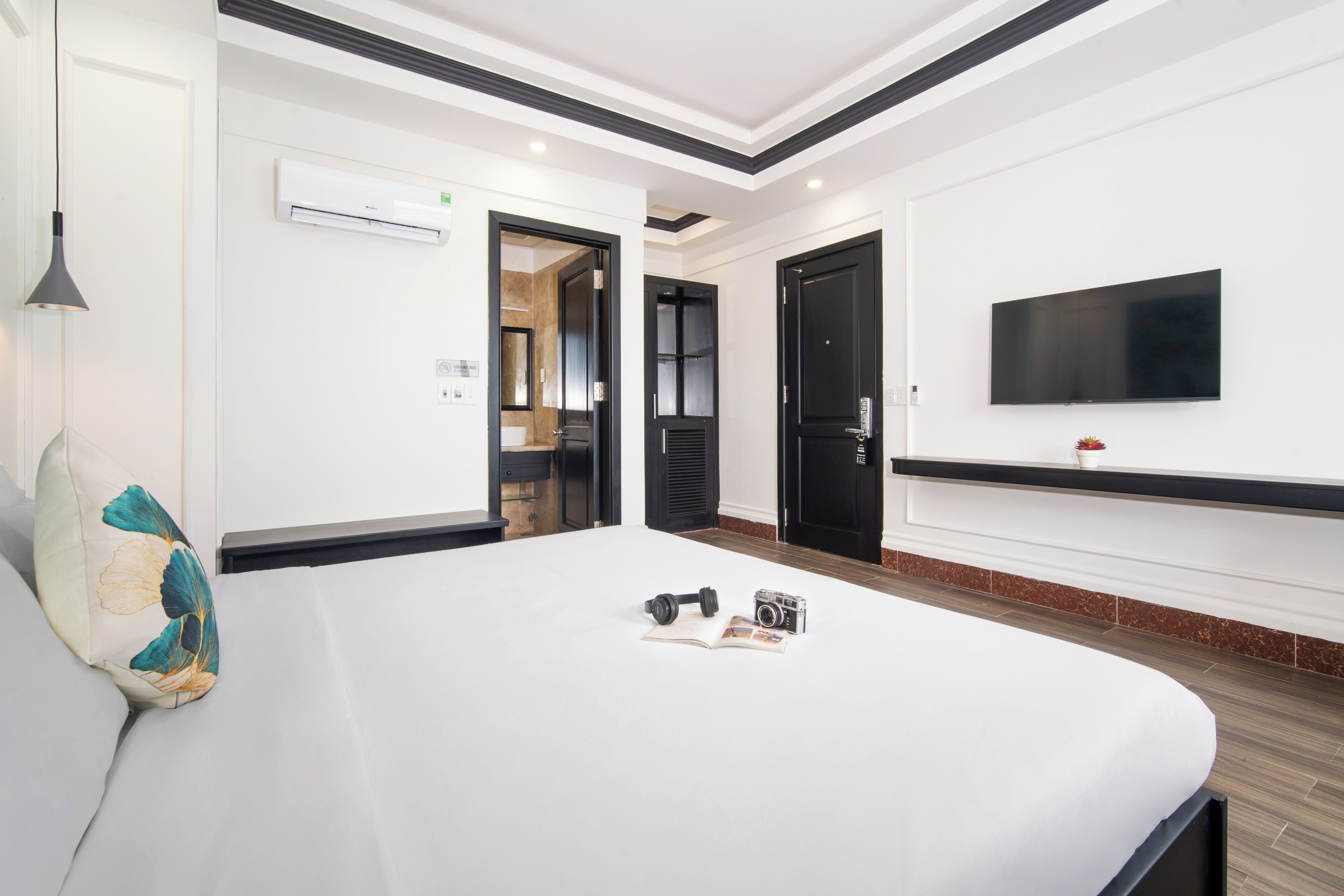 A modern hotel room with a large bed, a flat-screen TV mounted on the wall, and a door leading to a bathroom.