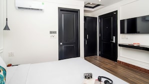 Ett modernt hotellrum med en säng, ett skrivbord, en platt-TV och en garderob.