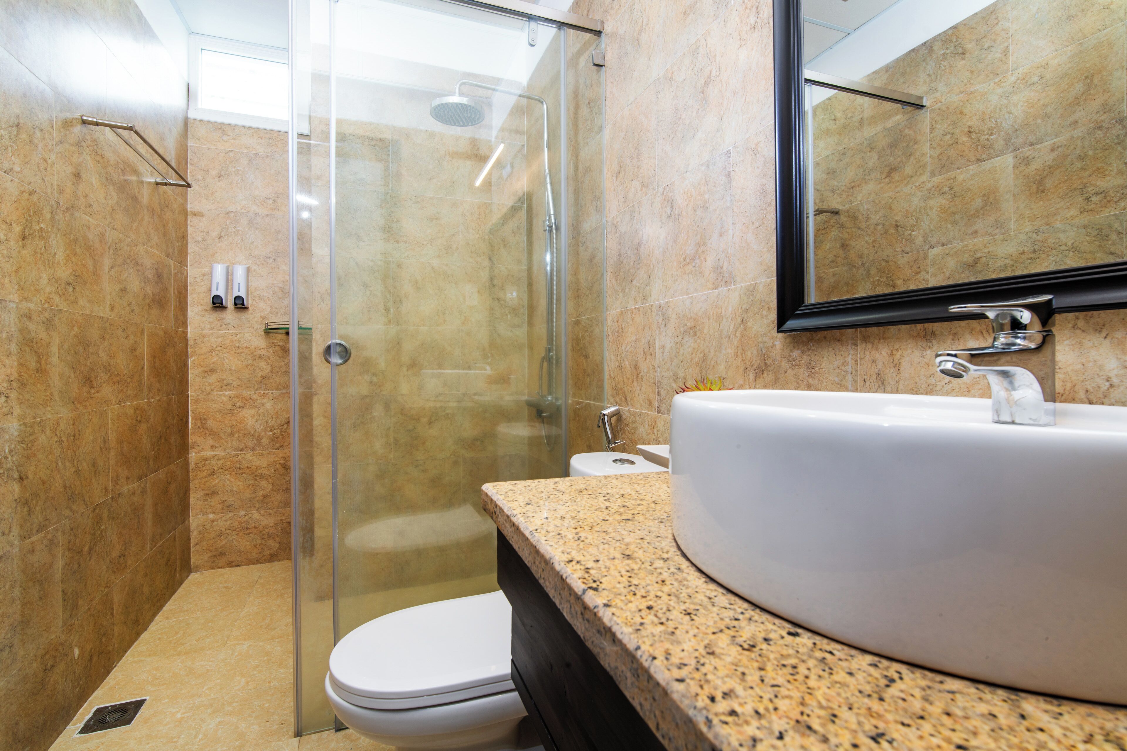 A modern bathroom with a glass-enclosed shower, a white sink, and a large mirror.