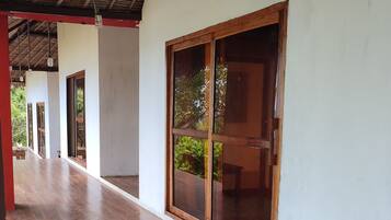 Una terraza cubierta de madera con grandes puertas correderas de vidrio y un techo de paja.