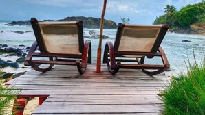 A wooden deck with two rocking chairs and an orange umbrella.