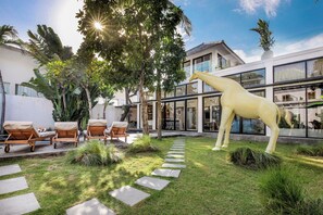 Relax in a serene outdoor space with a beautifully manicured lawn, lounge chairs, and a dining table.