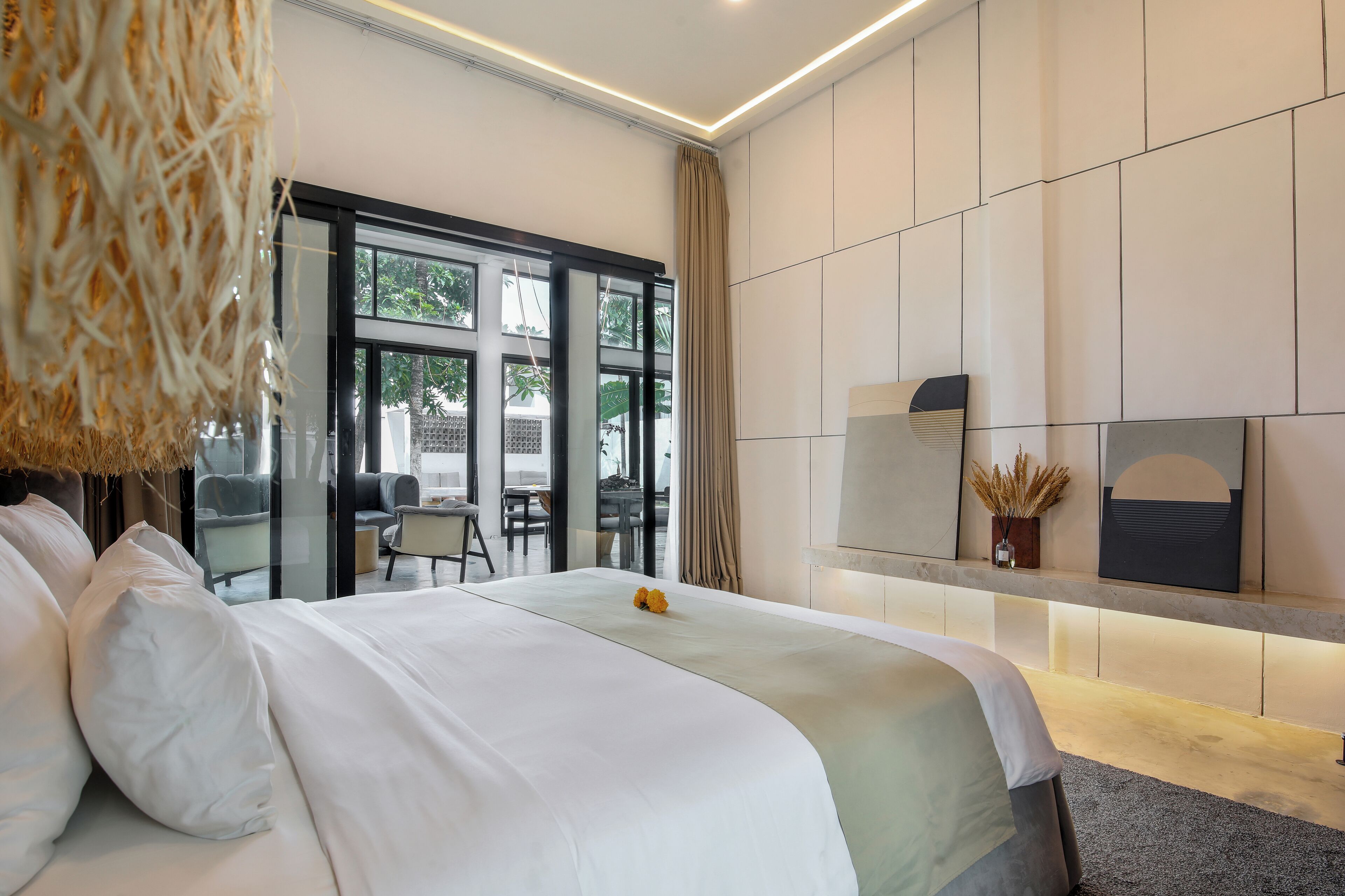 A modern hotel room with a large bed, a desk, and a view of the outdoors.