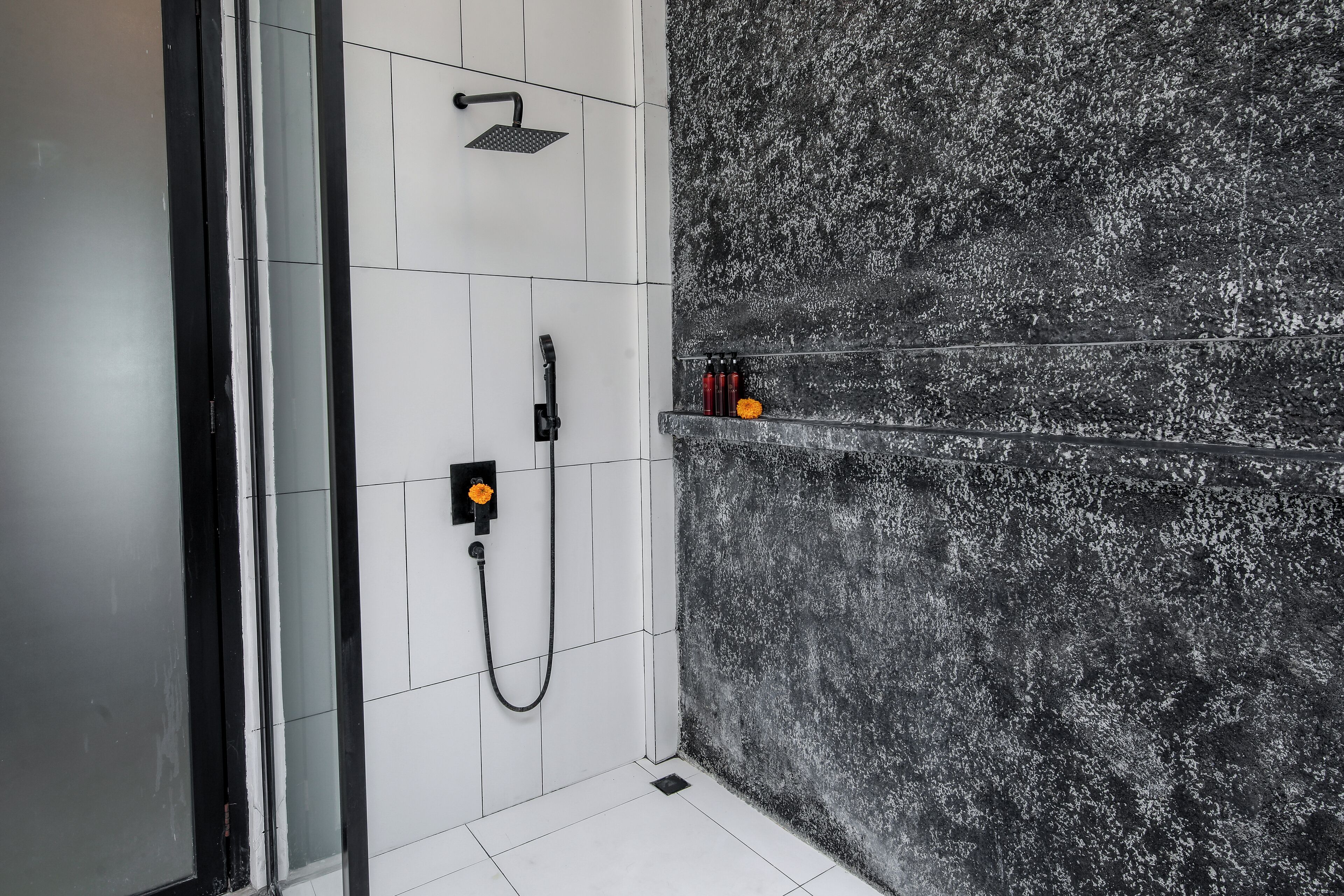Ein Badezimmer mit Dusche, einer Glasabtrennung und Ablage für Toilettenartikel.