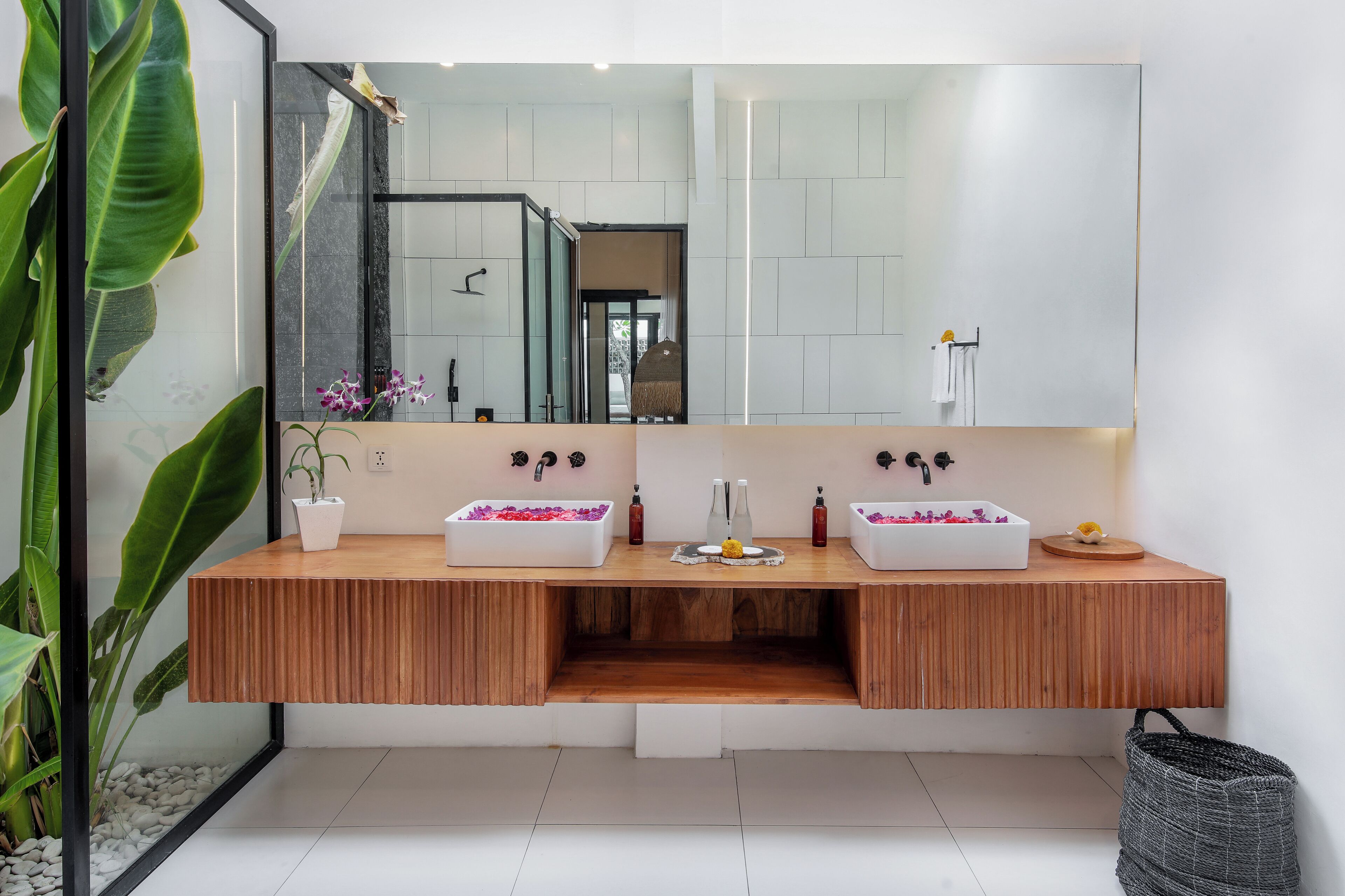 A modern bathroom with a wooden vanity, two sinks, and a large mirror.
