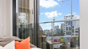 Una habitación con un ventanal que ofrece vistas a un paisaje urbano, incluyendo una torre y edificios.