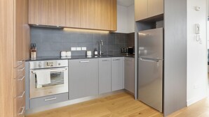 Una cocina moderna con armarios grises, un refrigerador de acero inoxidable y un horno empotrado.