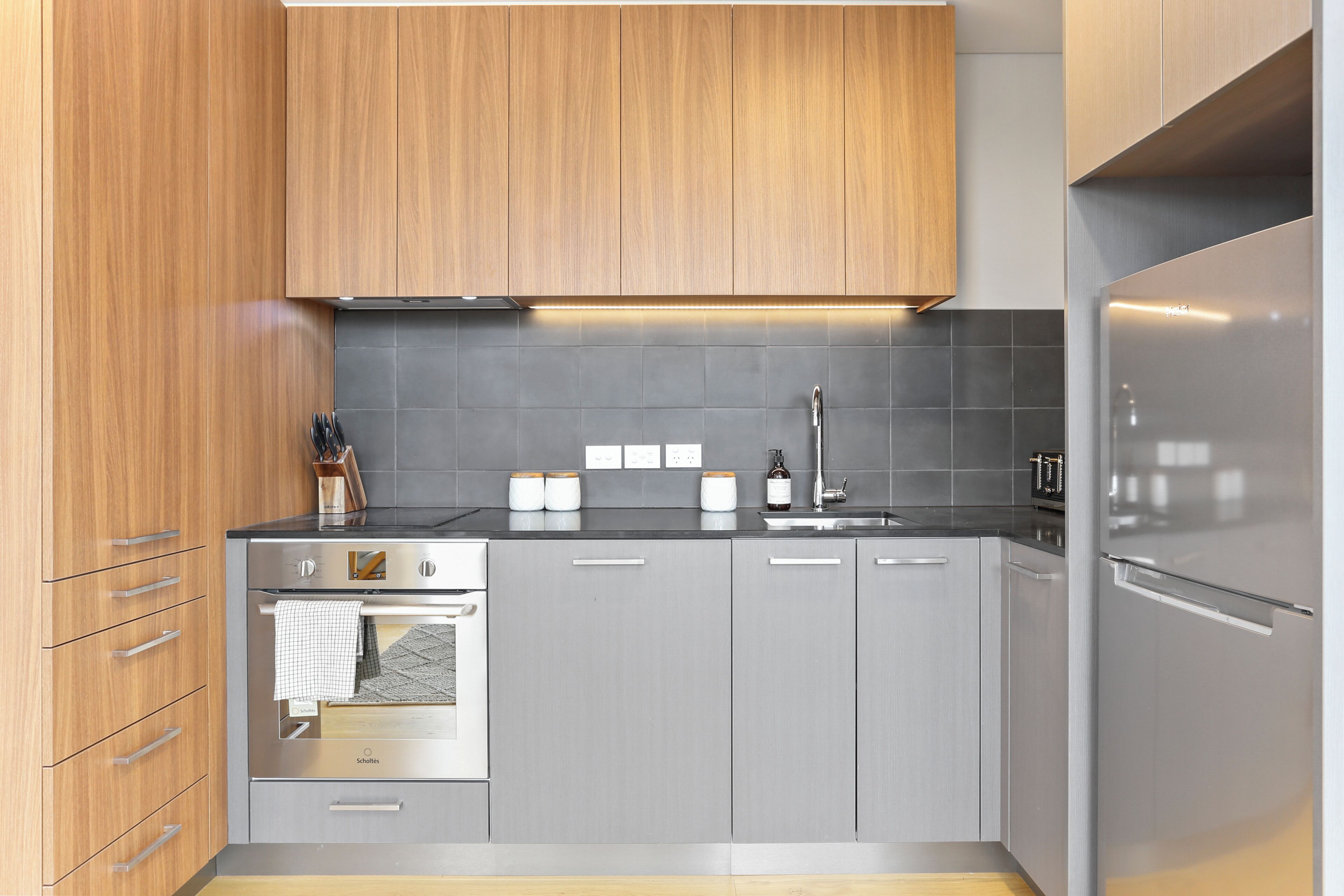 Eine moderne Küche mit Holzschränken, einem Edelstahlbackofen und einem eingebauten Geschirrspüler.