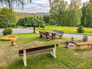 Relax in a serene outdoor space with benches, picnic tables, and a sandbox for kids to play.