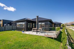 A modern house with a deck, a large window, and a clear sky. - Views on Farrant Summ (Wānaka)