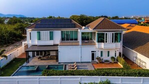 A two-story house with a swimming pool, solar panels, and a balcony. - Luxury 4 Bedroom Pool Villa - PV8 (Hua Hin)