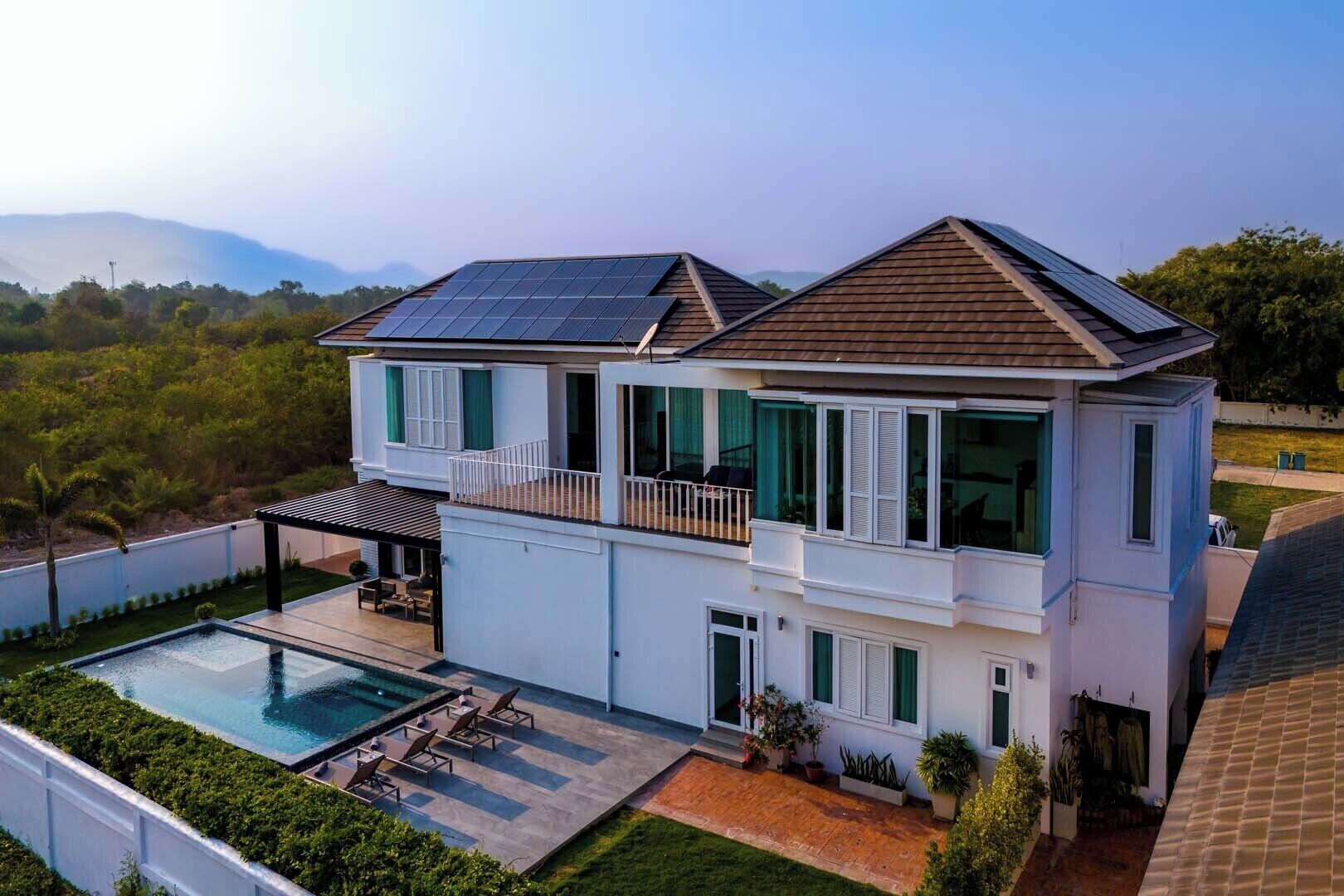 A modern two-story house with solar panels, a swimming pool, and a well-maintained garden.